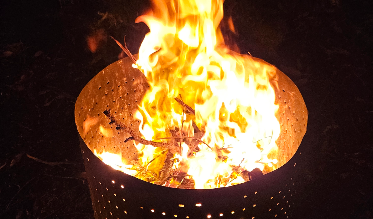 A hot camp fire with high flames in a metal drum